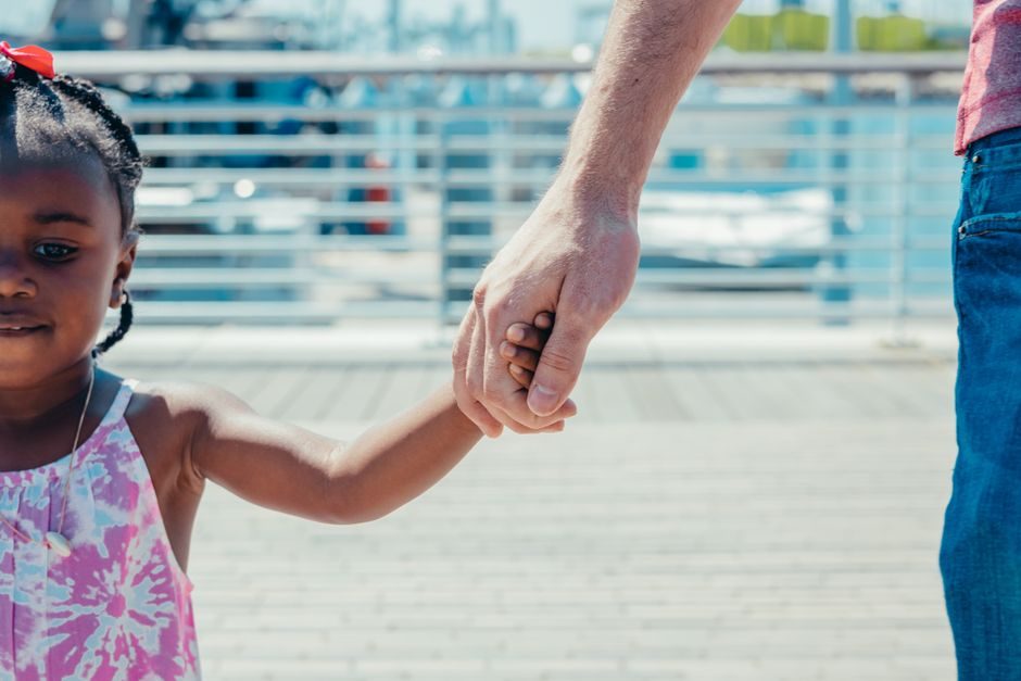 Main d'un enfant tenue par un adulte, protection des mineurs